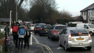 A traffic jam on Rymers Lane Oxford, with three children huddled on the pavement